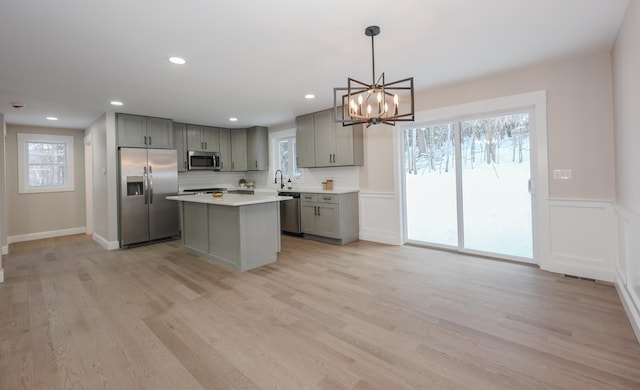 kitchen featuring a kitchen island, light countertops, decorative light fixtures, gray cabinets, and stainless steel appliances