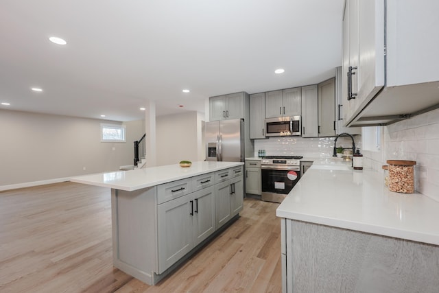 kitchen featuring a center island, tasteful backsplash, light countertops, stainless steel appliances, and a sink