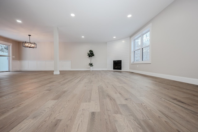 unfurnished living room with a large fireplace, light wood-style flooring, plenty of natural light, and recessed lighting