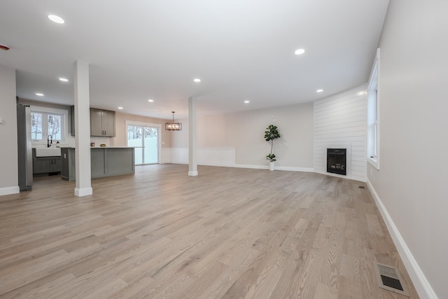 unfurnished living room with a sink, recessed lighting, visible vents, light wood-style floors, and a fireplace