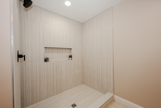 full bathroom featuring baseboards and tiled shower