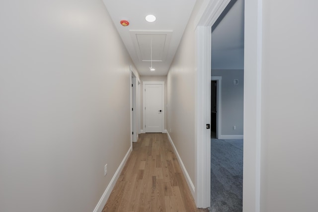 hall with attic access, baseboards, and light wood-style floors