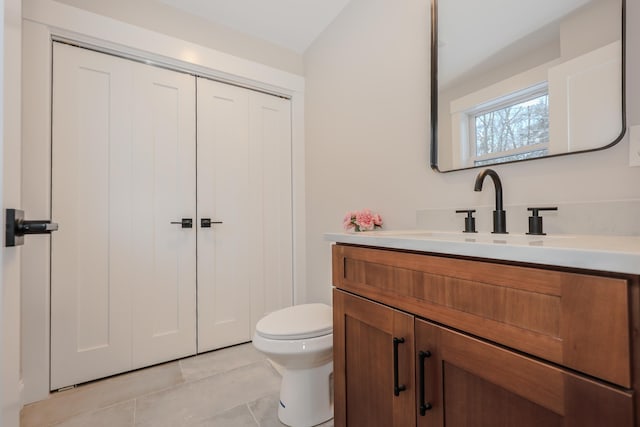 bathroom featuring a closet, vanity, tile patterned flooring, and toilet