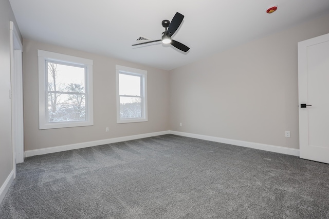 empty room with baseboards, a ceiling fan, dark carpet, and visible vents