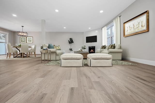 living room featuring a wealth of natural light, a large fireplace, and light wood-style floors