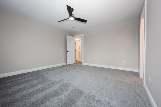 carpeted spare room featuring baseboards and ceiling fan