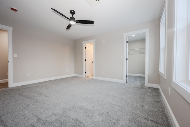 unfurnished bedroom with ceiling fan, a spacious closet, light carpet, and a closet