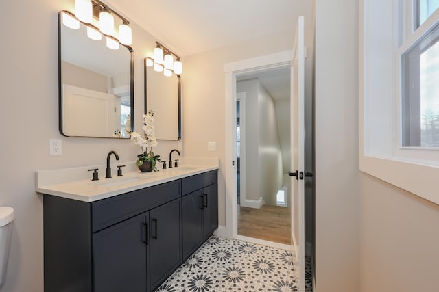 bathroom with a sink, toilet, double vanity, and tile patterned floors