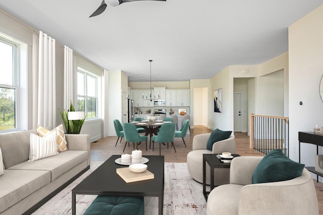 living room with plenty of natural light, ceiling fan with notable chandelier, and light hardwood / wood-style flooring