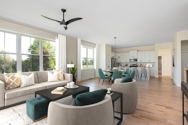 living room featuring ceiling fan with notable chandelier and light hardwood / wood-style flooring