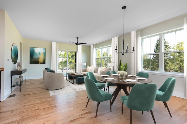 dining room with ceiling fan with notable chandelier and light wood-type flooring