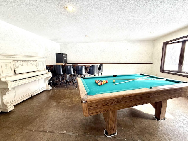 rec room with pool table, bar area, and a textured ceiling