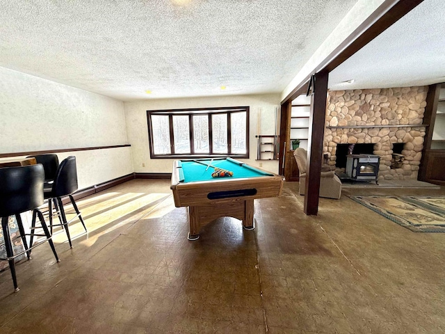 rec room featuring pool table, a textured ceiling, and a wood stove