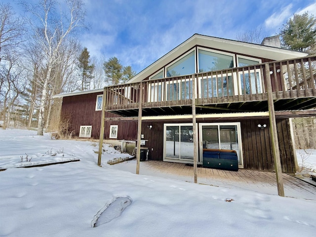 snow covered back of property featuring a wooden deck