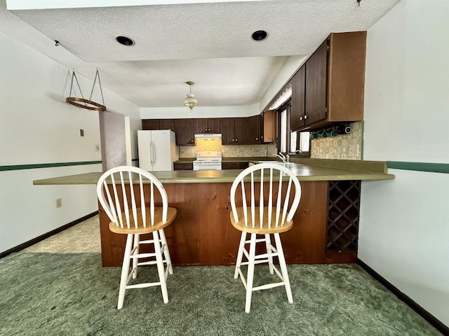 kitchen with tasteful backsplash, white appliances, dark brown cabinets, and kitchen peninsula