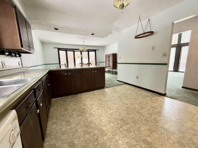 kitchen with dark brown cabinets, sink, white dishwasher, and decorative light fixtures