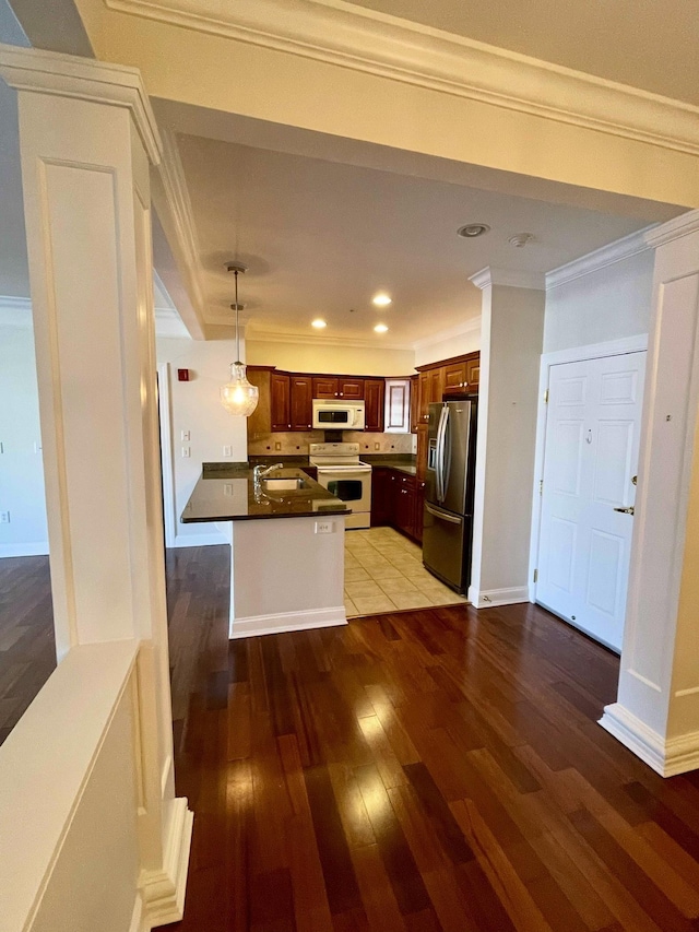 kitchen with pendant lighting, sink, white appliances, dark wood-type flooring, and ornamental molding