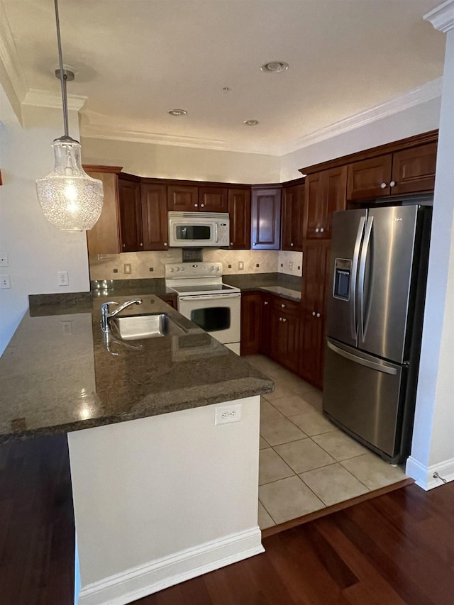 kitchen featuring tasteful backsplash, pendant lighting, white appliances, and kitchen peninsula