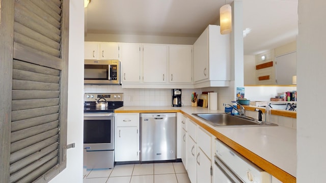 kitchen with pendant lighting, sink, stainless steel appliances, and white cabinets