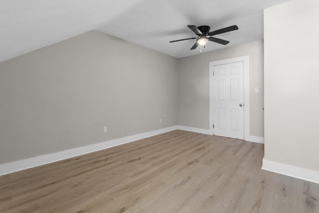 empty room with ceiling fan, vaulted ceiling, and light hardwood / wood-style floors