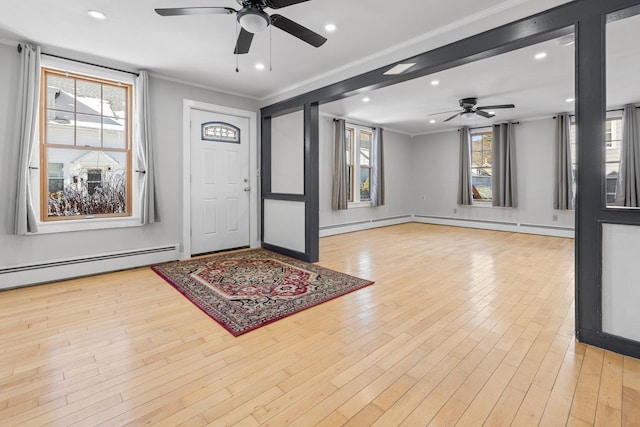 foyer with ceiling fan, ornamental molding, a baseboard heating unit, and light wood-type flooring