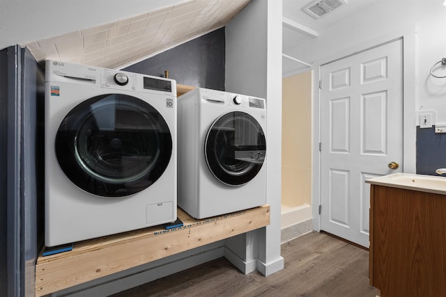 clothes washing area with sink, hardwood / wood-style floors, and washing machine and dryer