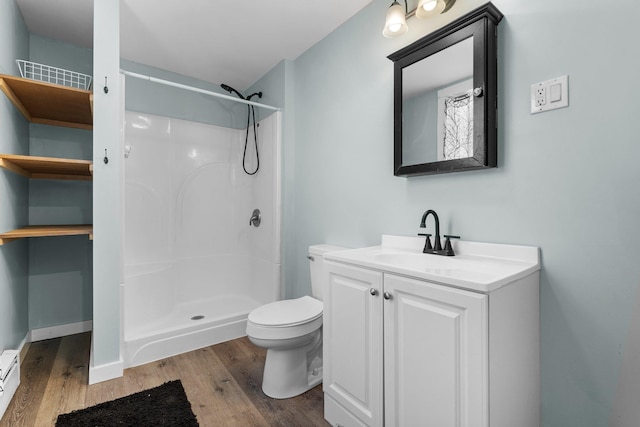 bathroom with hardwood / wood-style flooring, vanity, walk in shower, a baseboard heating unit, and toilet