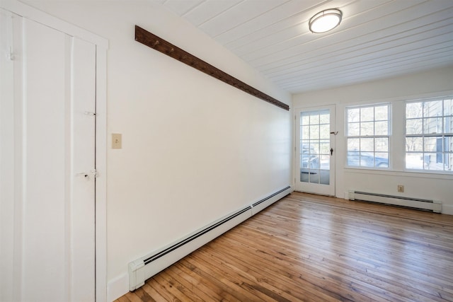 spare room with beam ceiling, baseboard heating, and light hardwood / wood-style flooring