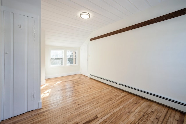 unfurnished room with baseboard heating, lofted ceiling with beams, and light hardwood / wood-style flooring