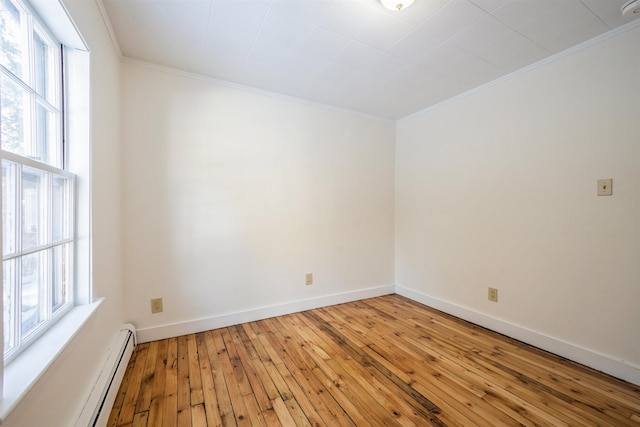 spare room with a baseboard heating unit, crown molding, a healthy amount of sunlight, and hardwood / wood-style floors