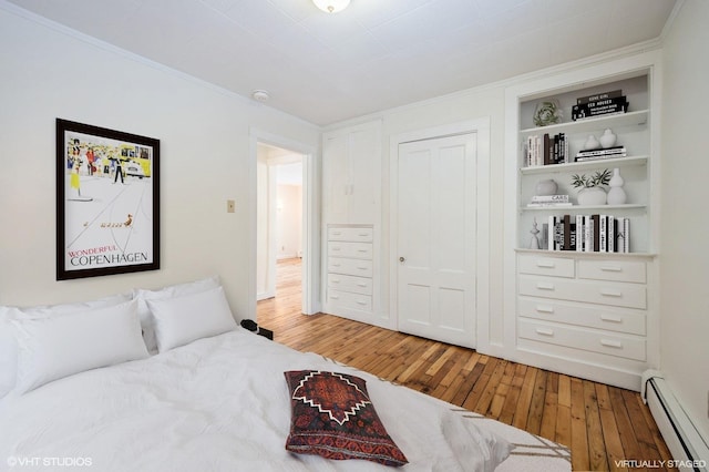 bedroom with wood-type flooring, baseboard heating, and a closet