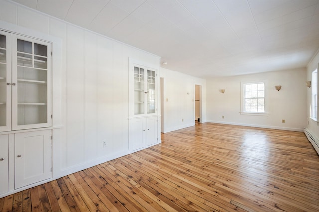 spare room featuring built in features and light hardwood / wood-style floors