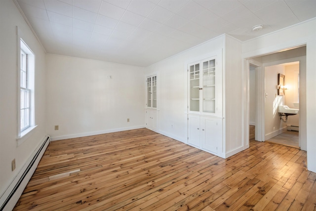 unfurnished room featuring light hardwood / wood-style flooring, ornamental molding, and baseboard heating