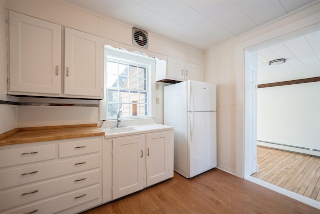 kitchen with white cabinetry, white fridge, and baseboard heating