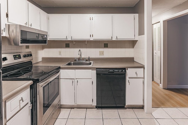 kitchen featuring white cabinetry, stainless steel appliances, sink, and light tile patterned floors