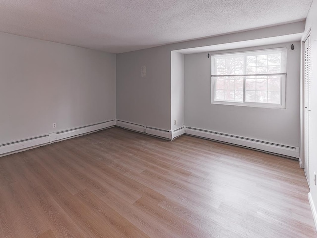 unfurnished room featuring a baseboard heating unit, light hardwood / wood-style flooring, and a textured ceiling