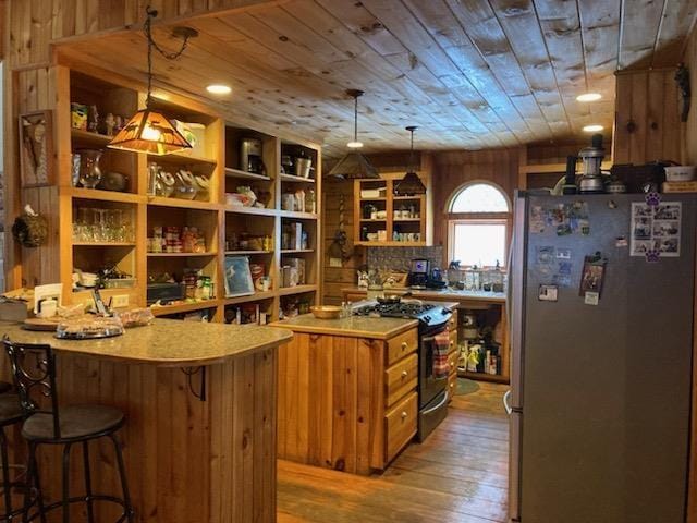 kitchen featuring black stove, wood ceiling, stainless steel refrigerator, and decorative light fixtures