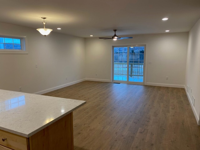 unfurnished living room featuring dark wood-type flooring and ceiling fan