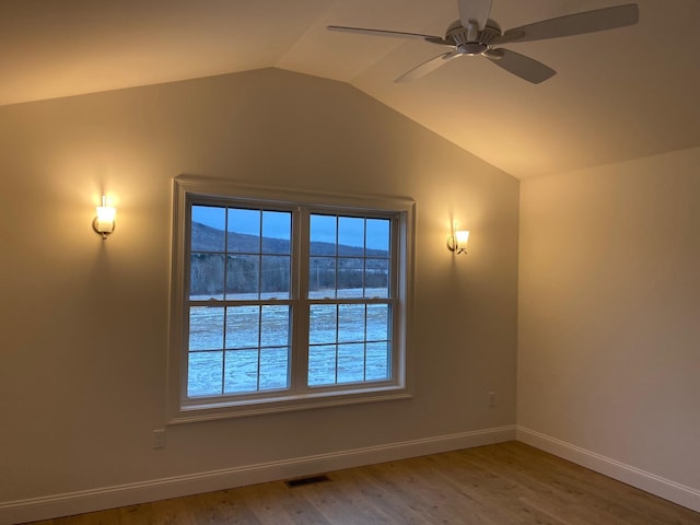 empty room with hardwood / wood-style flooring, a mountain view, lofted ceiling, and ceiling fan