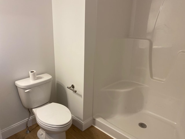 bathroom with walk in shower, toilet, and hardwood / wood-style floors