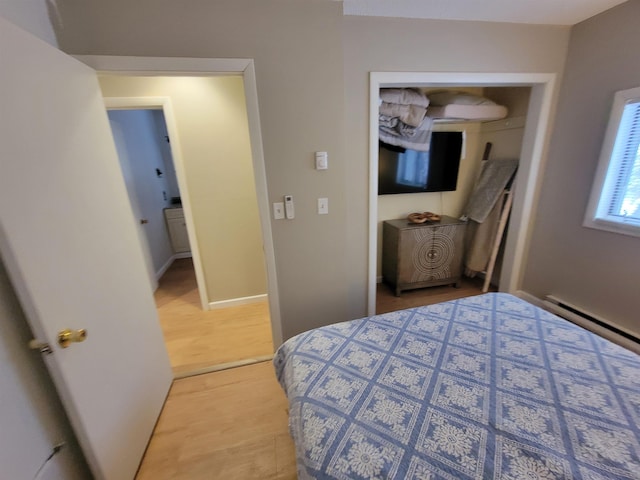 bedroom featuring hardwood / wood-style flooring, a baseboard radiator, and a closet