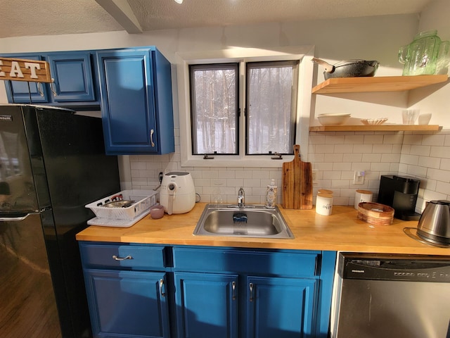 kitchen with blue cabinets, sink, black fridge, tasteful backsplash, and stainless steel dishwasher