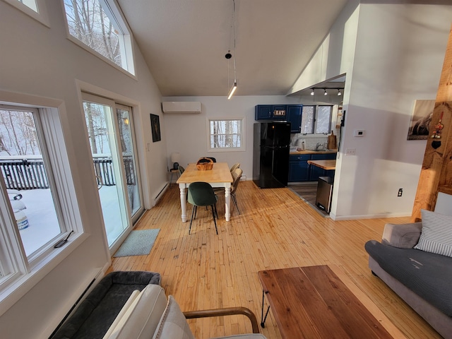 dining space featuring a baseboard heating unit, a wealth of natural light, a wall unit AC, and light hardwood / wood-style floors