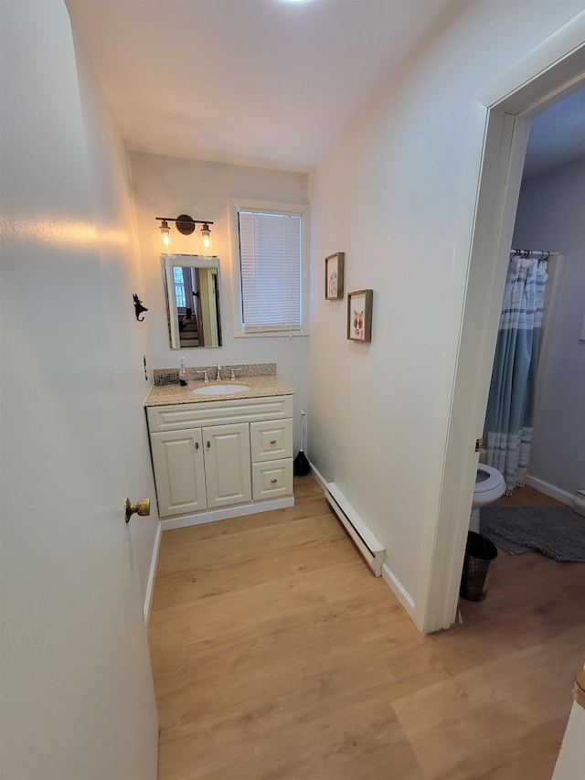 bathroom with vanity, a baseboard heating unit, hardwood / wood-style floors, and toilet