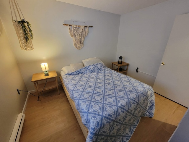 bedroom with light hardwood / wood-style floors and a baseboard heating unit