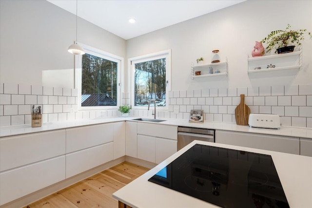 kitchen with pendant lighting, sink, white cabinets, stainless steel dishwasher, and black electric cooktop