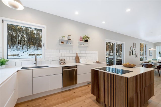 kitchen with a kitchen island, white cabinetry, sink, decorative backsplash, and stainless steel dishwasher