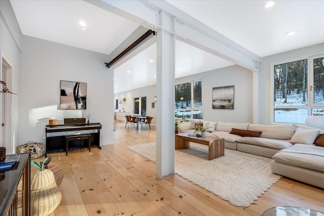 living room featuring beam ceiling, light hardwood / wood-style floors, and decorative columns