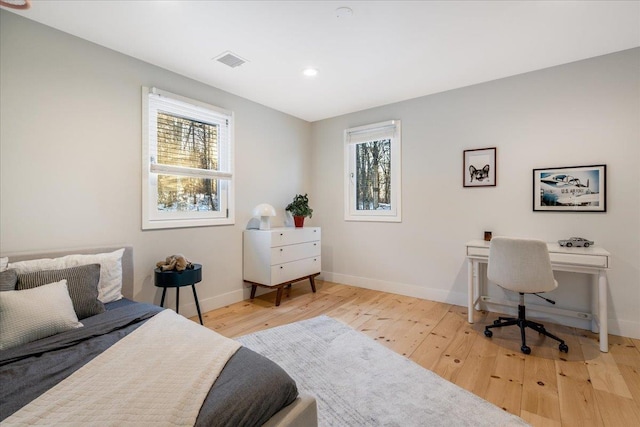 bedroom with multiple windows and light wood-type flooring