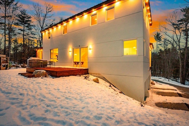 snow covered back of property with a patio